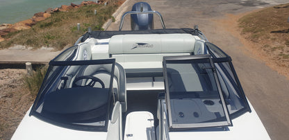 White boat with open sides on a dirt road near water