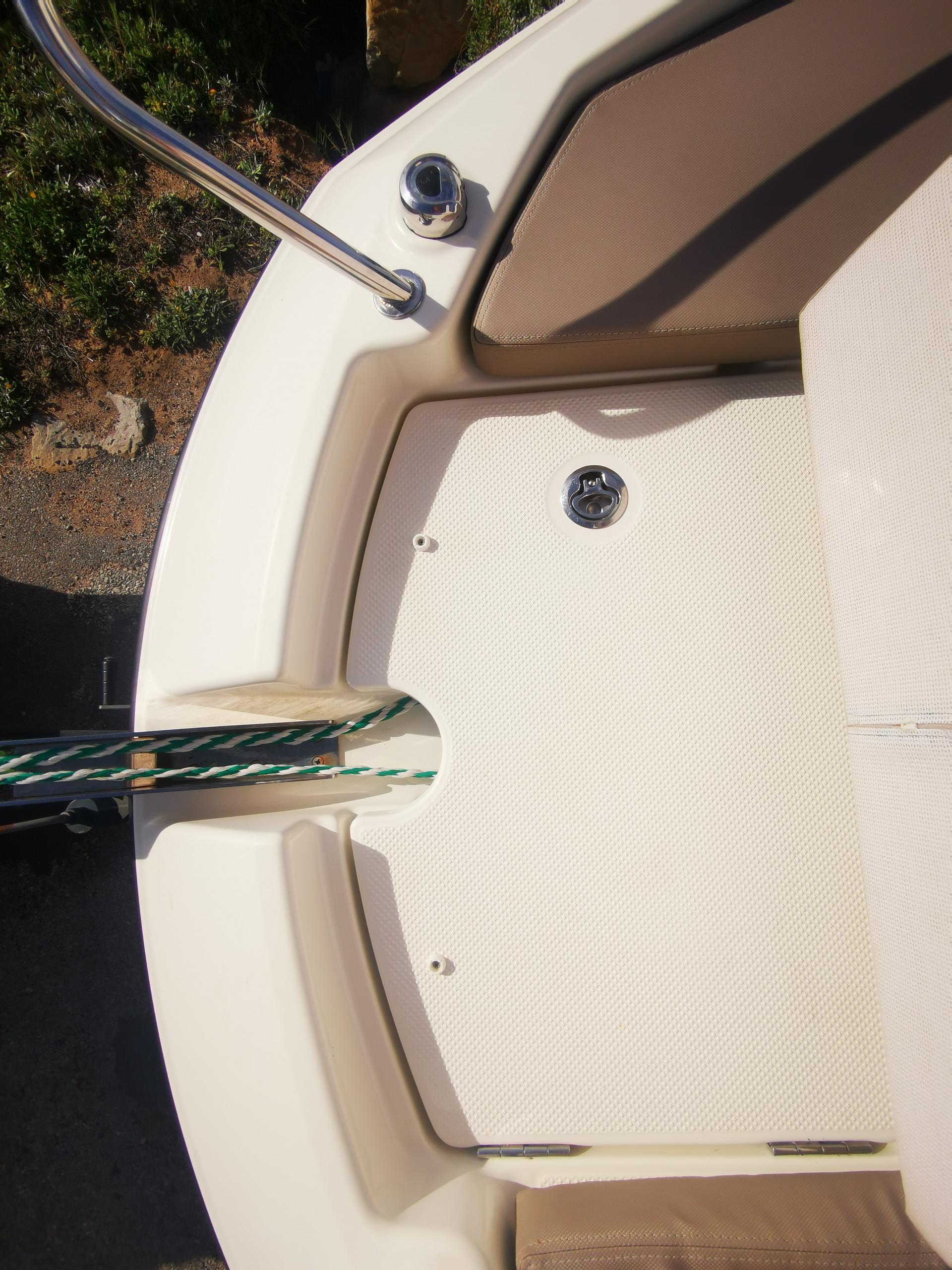 Close-up of a boat's interior with beige cushioned seats and metal railings.