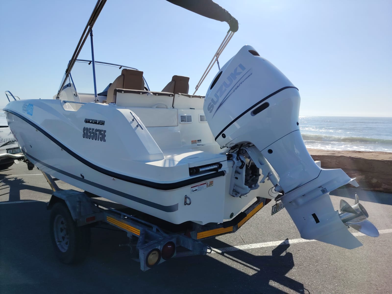 White boat with outboard motor on a trailer by the beach