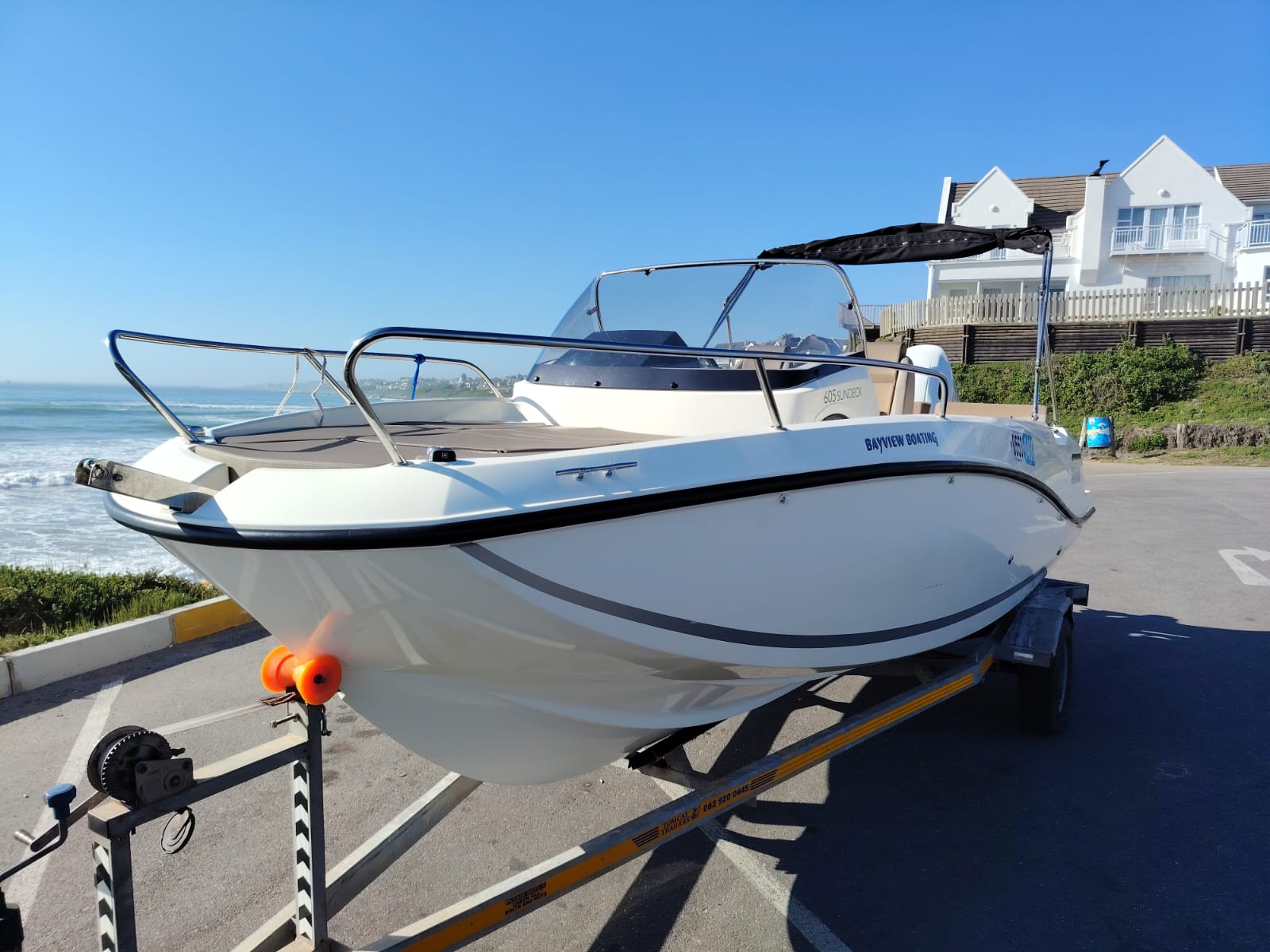 White speedboat on a trailer by the beach with clear blue sky