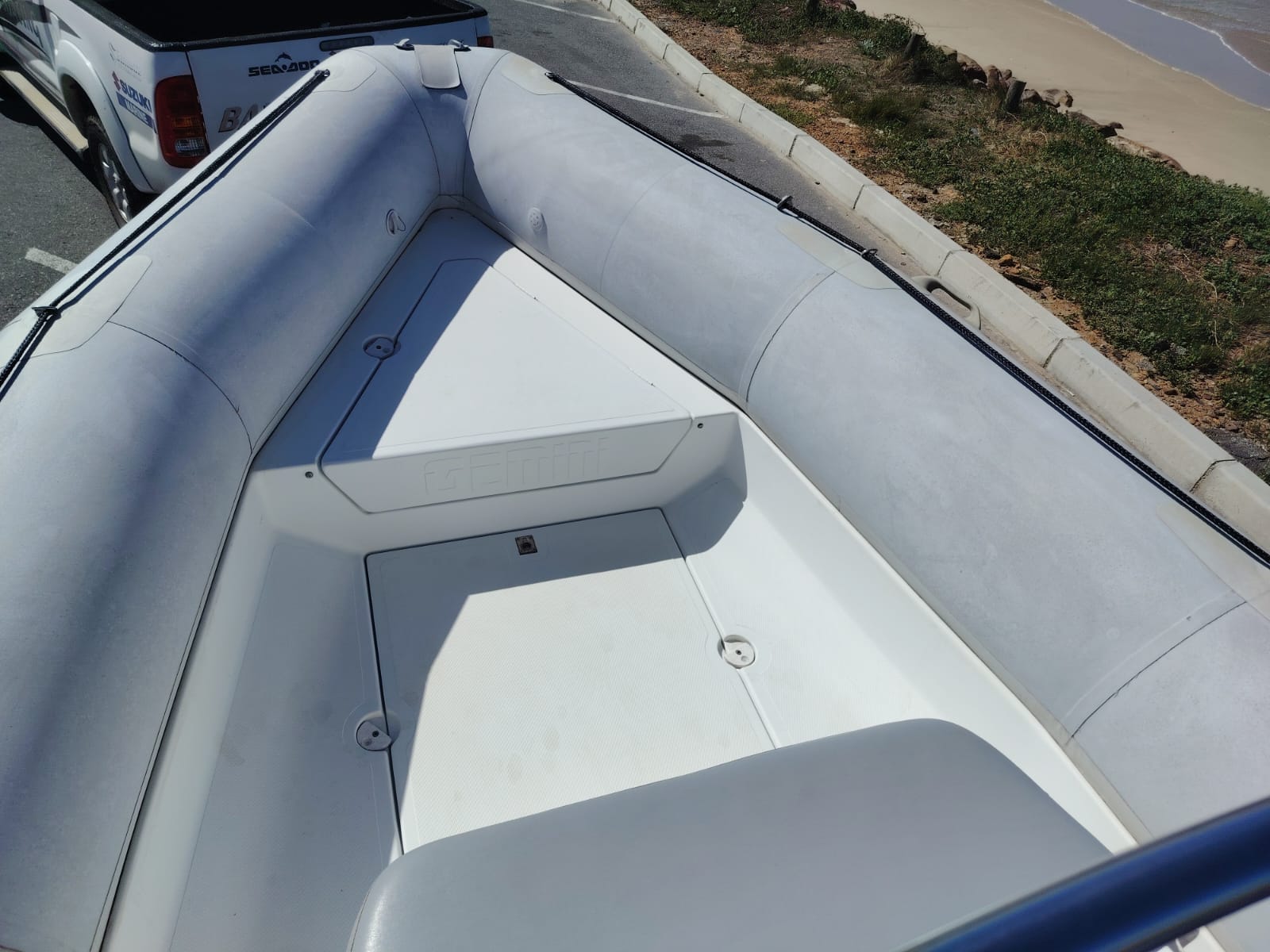 Inflatable boat on a paved road with a white truck in the background