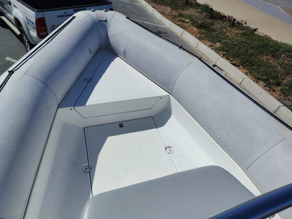 Inflatable boat on a paved road with a white truck in the background