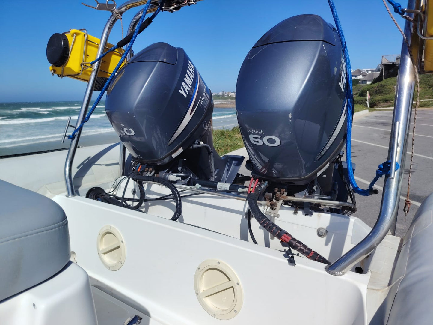 Two Yamaha outboard motors on a boat with a beach and ocean in the background.
