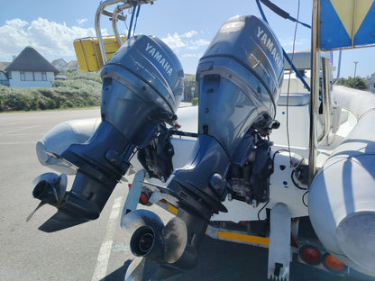 Two Yamaha outboard motors on a boat in a parking lot with a clear sky.
