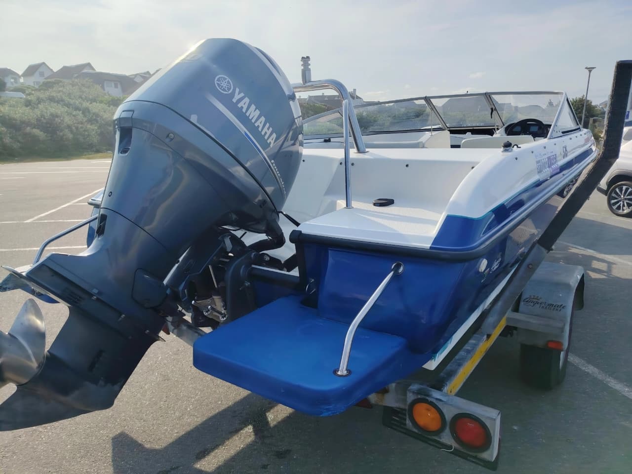 Blue and white Kestrel 575 boat with a Yamaha 150HP four-stroke outboard and trailer.