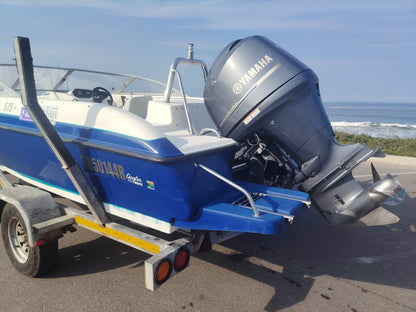 Blue and white Kestrel 575 boat with a Yamaha 150HP four-stroke outboard and trailer.