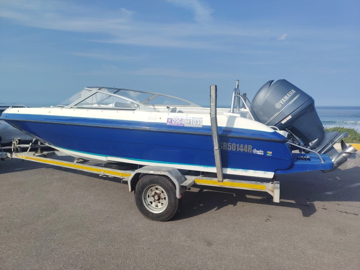 Blue and white Kestrel 575 boat with a Yamaha 150HP four-stroke outboard and trailer.