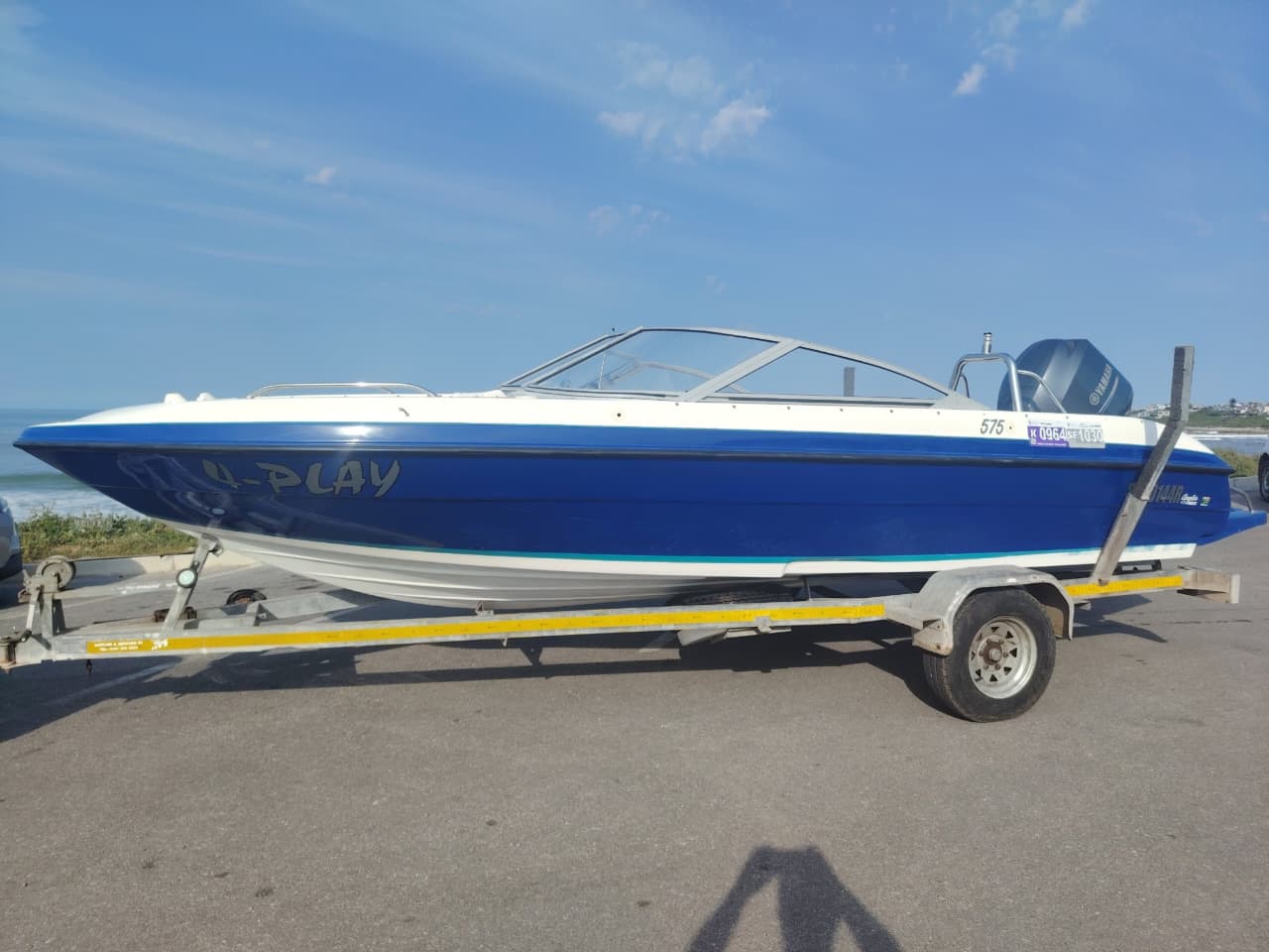 Blue and white Kestrel 575 boat with a Yamaha 150HP four-stroke outboard and trailer.
